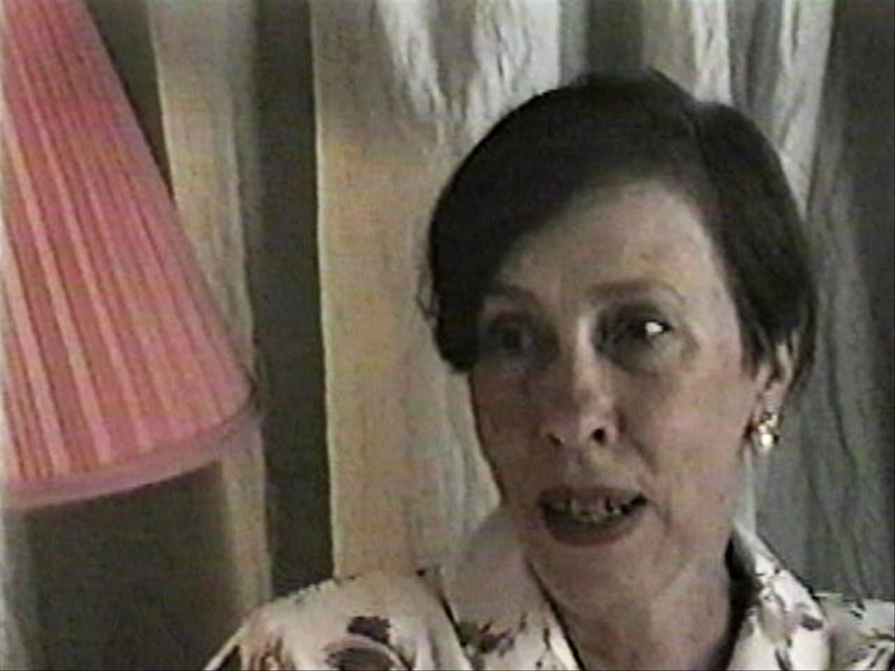 Medium shot of a woman speaking next to a lampshade