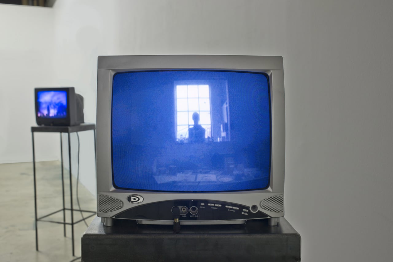 Closeup of a TV with violet-blue image of a woman at a window