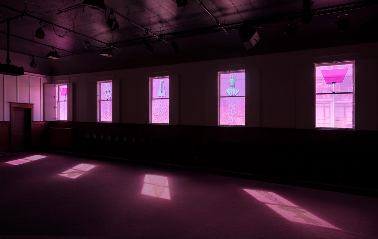 Interior, dim space with several windows with transparent pink images, like stained glass