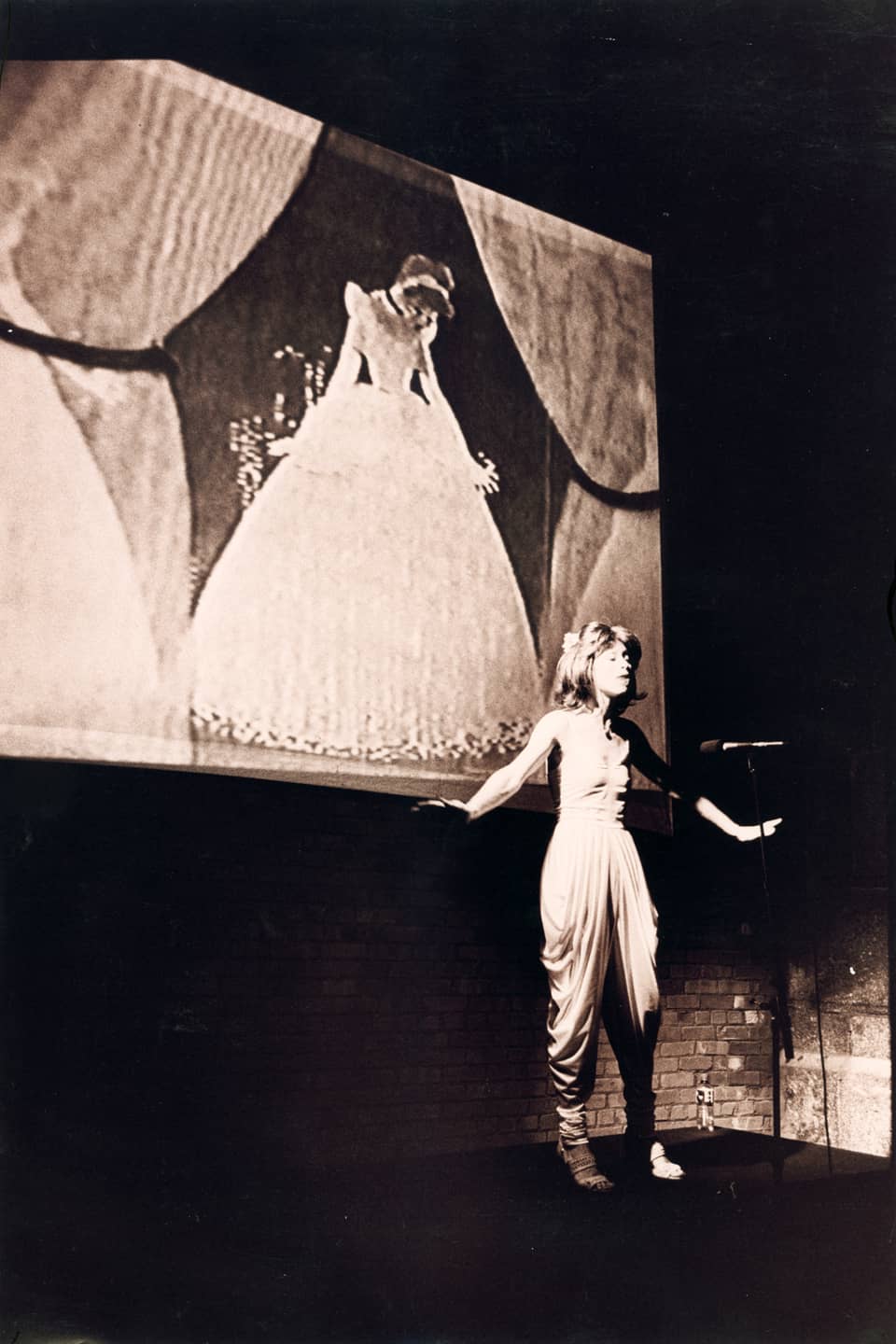 A woman performs on stage in front of a projection of Disney’s Cinderella